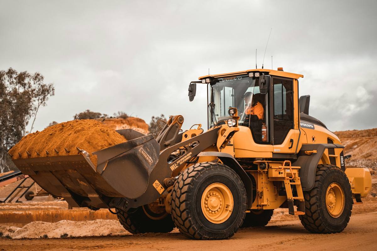 Front-end loader carrying a bucket of red dirt on a mine site